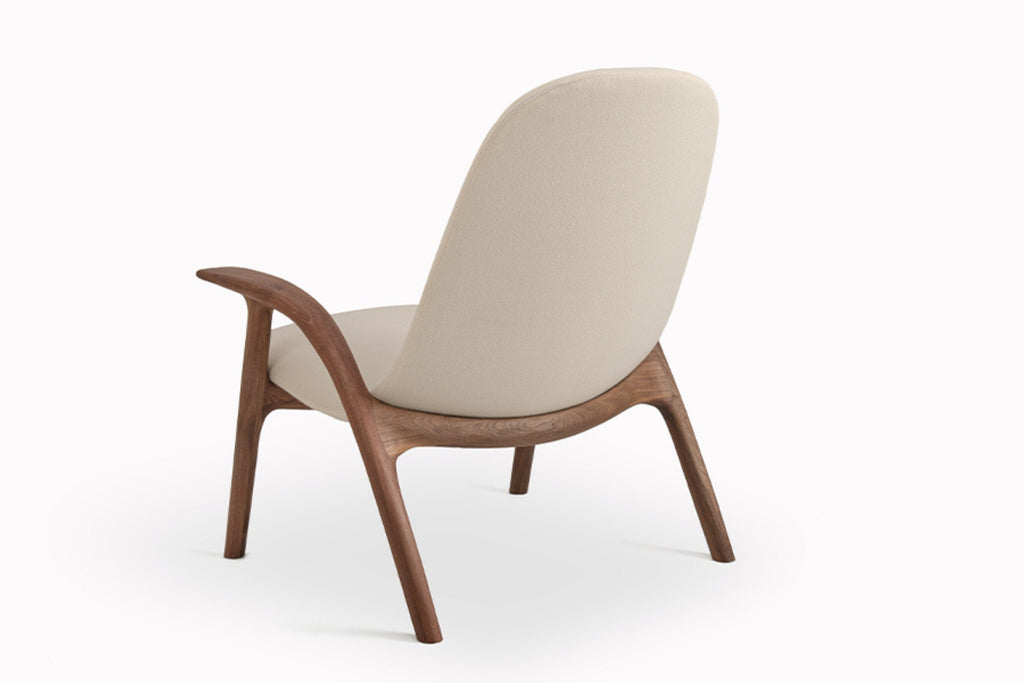 Rückansicht des ALPHA Designer Loungesessels von GoEs mit geschwungenem Holzrahmen und hellem Stoffbezug