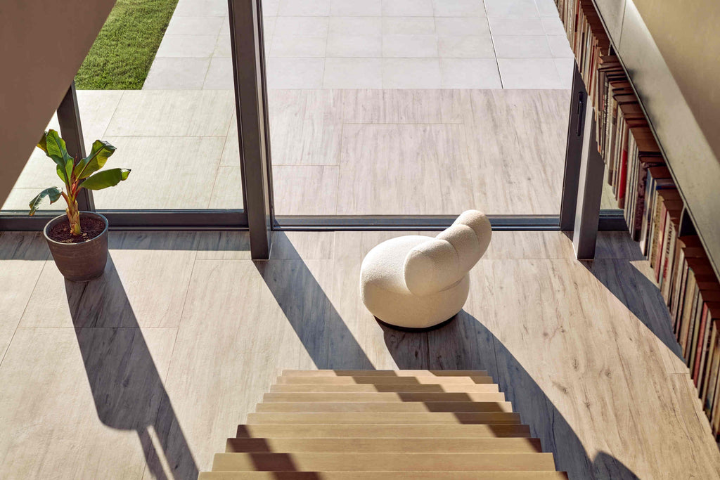 Designer Sessel in Beige in modernem Wohnbereich mit Treppe und Bücherwand