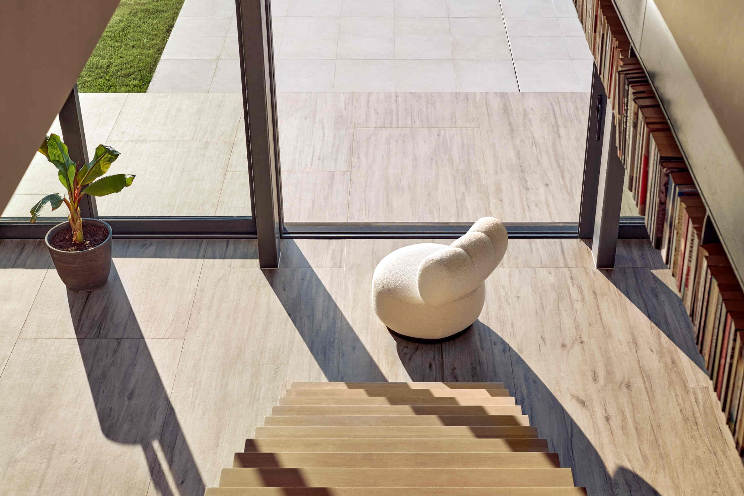 Designer Sessel in Beige in modernem Wohnbereich mit Treppe und Bücherwand