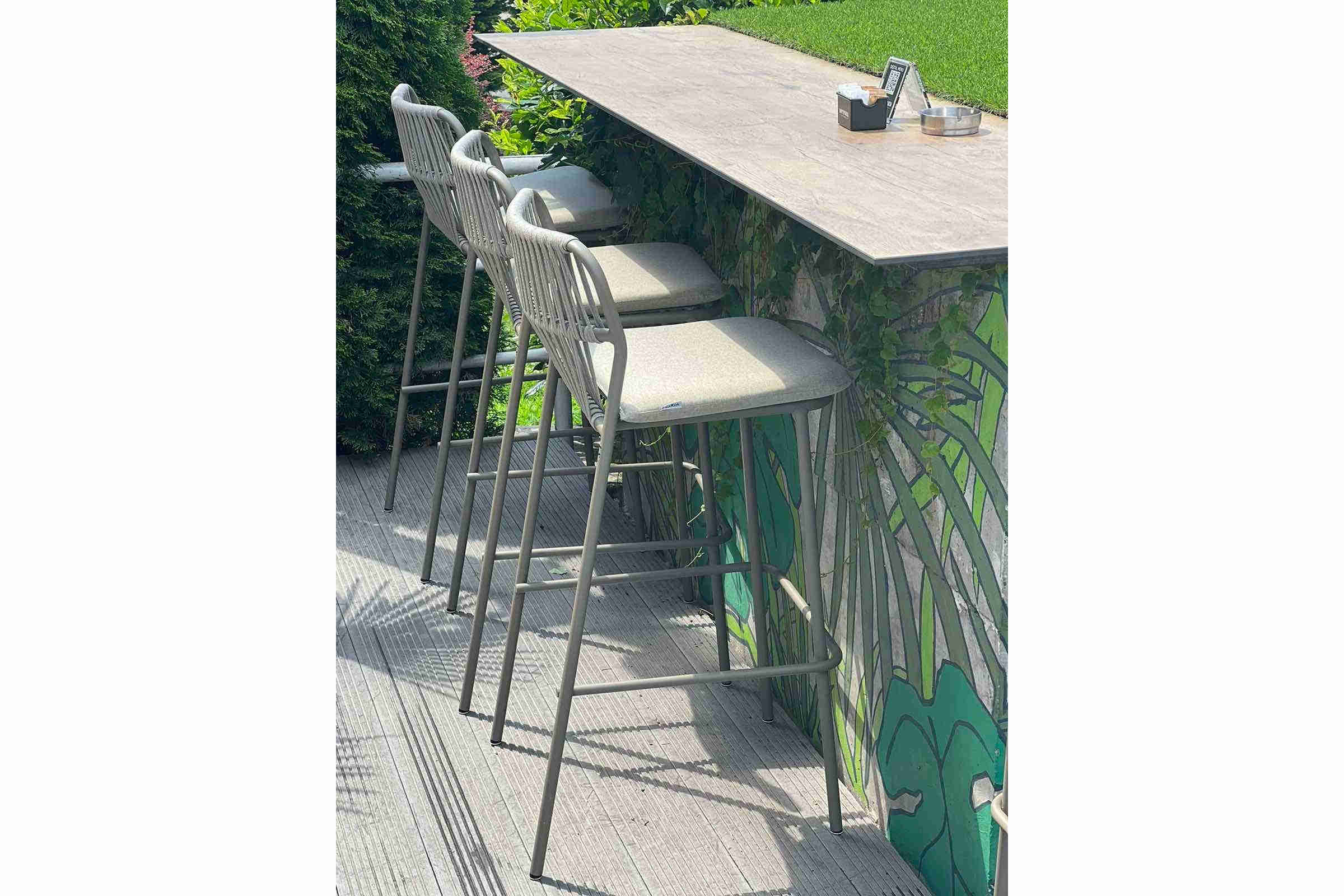 Mehrere BIANCA plus Gartenbarstühle an einer Outdoor-Bar im Gastronomiebereich
