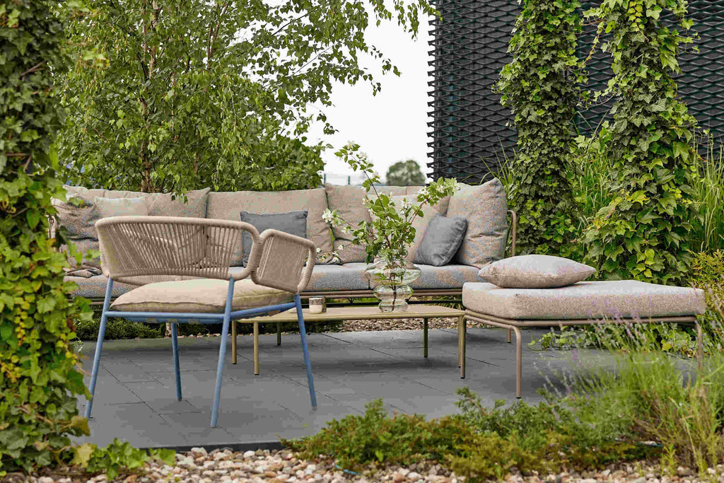 Gartenarmsessel als Teil einer Lounge-Szene mit Sofas und Liege