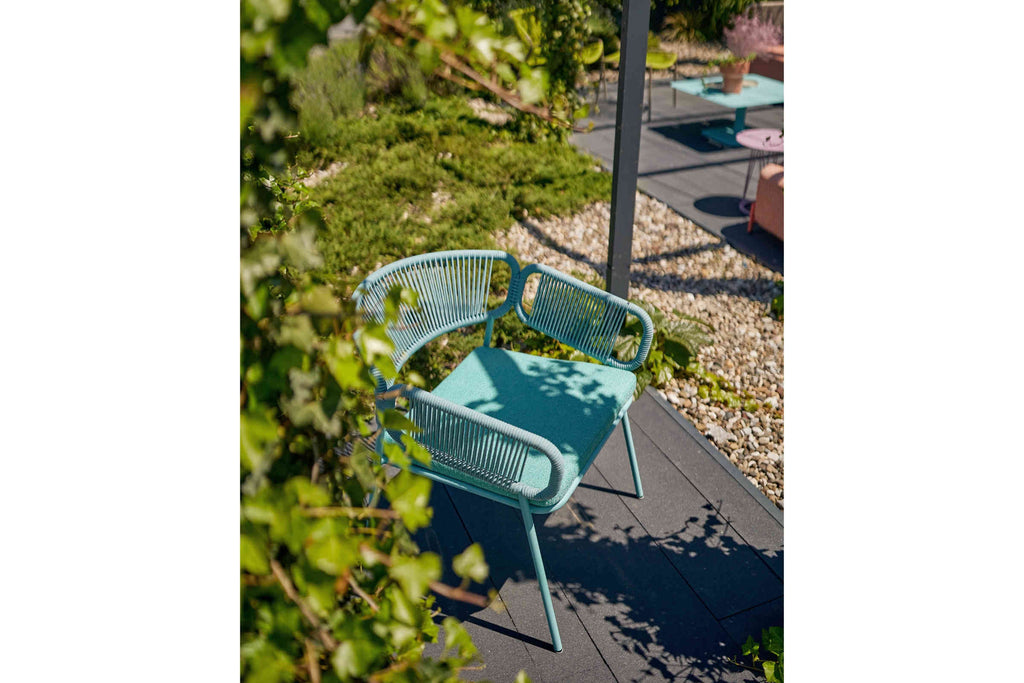 Gartensessel in Türkis auf Terrasse mit Kiesbett