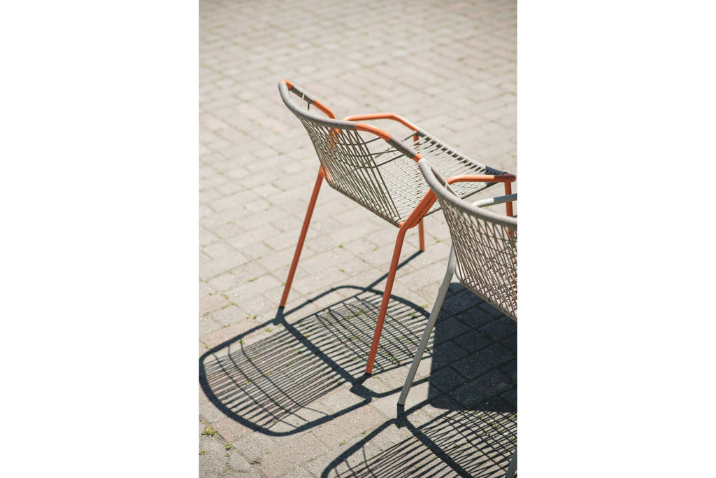 Zwei moderne Gartenstühle mit Seilbespannung im Freien auf Pflastersteinen