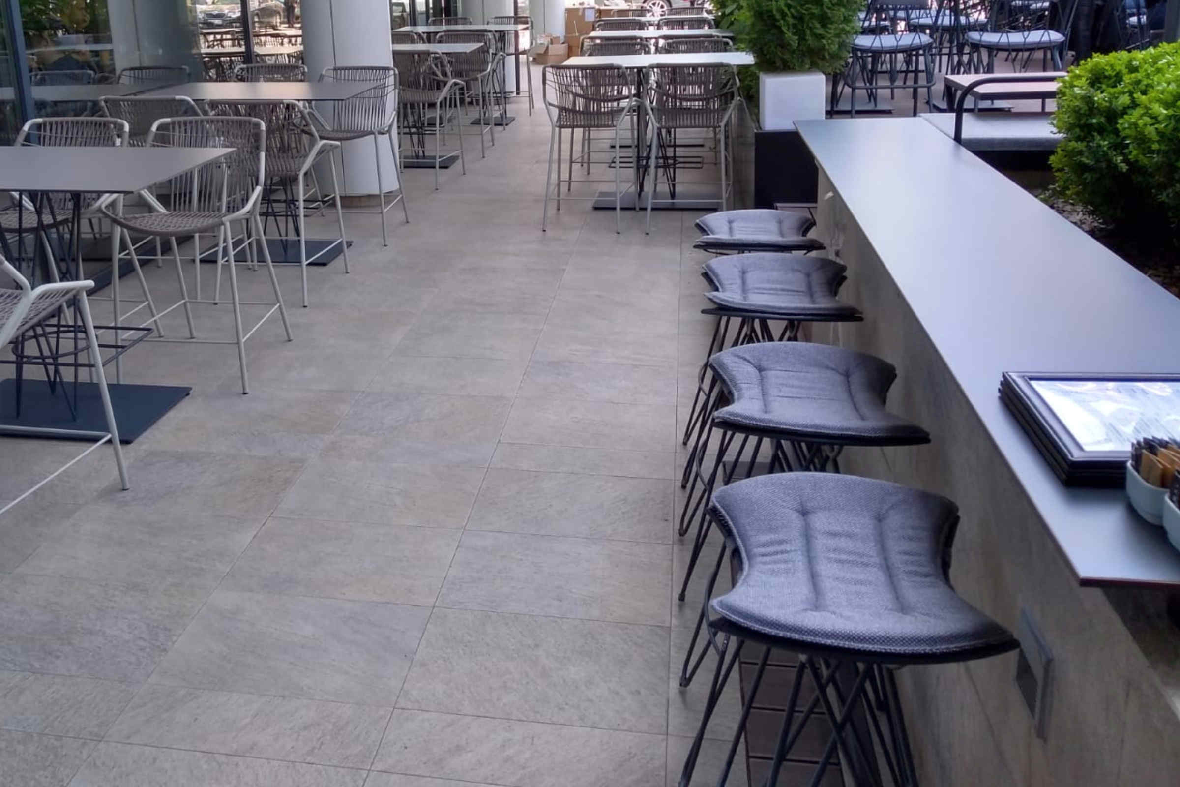 Mehrere gepolsterte Barhocker, ordentlich auf einer Terrasse aufgereiht