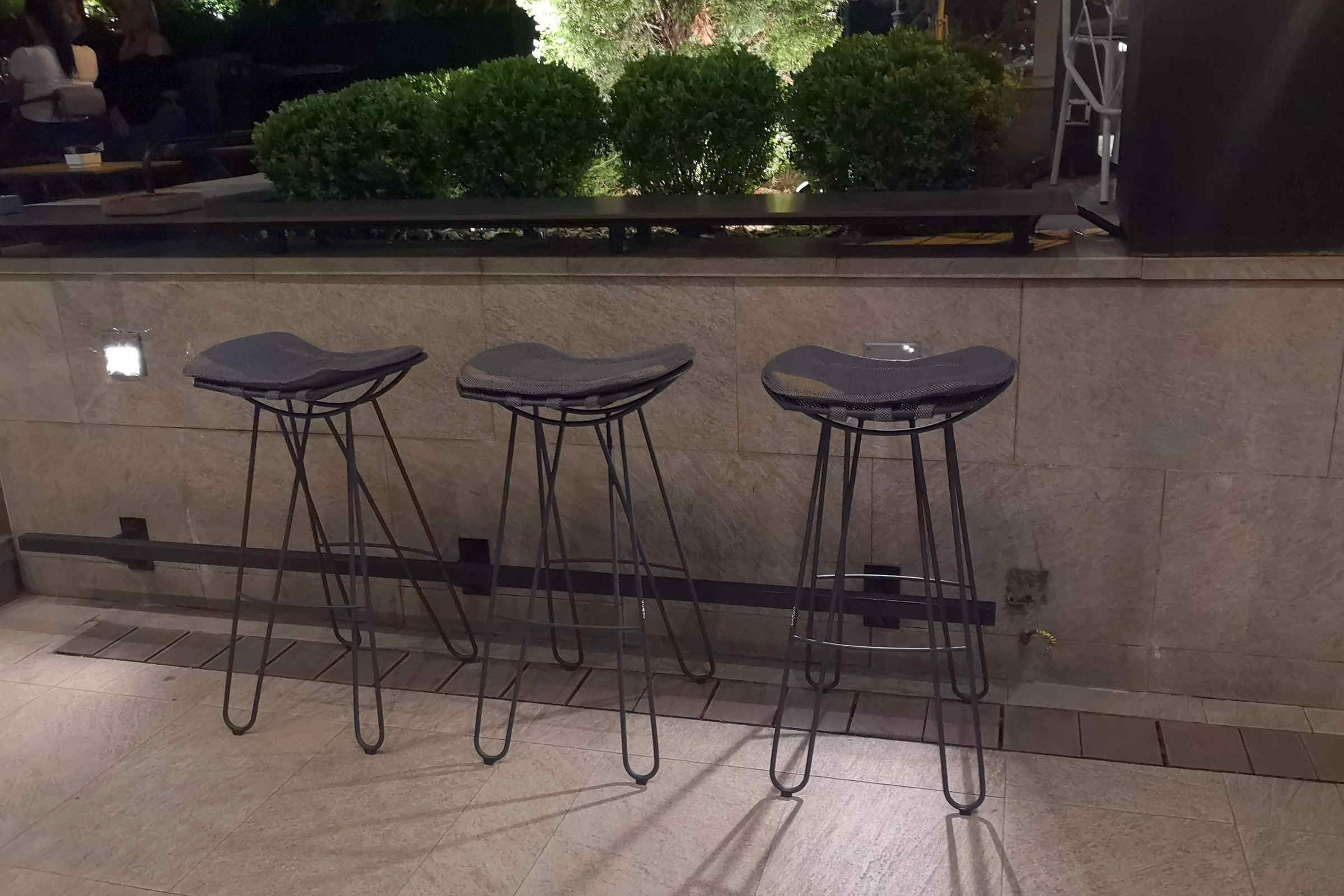 Drei Barhocker bei Nacht an einer Bar im Freien