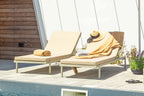 TOK Designer Sonnenliegen mit Handtüchern und Hut auf einer sonnigen Poolterrasse