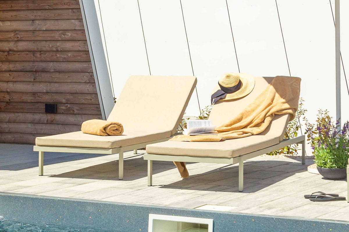 TOK Designer Sonnenliegen mit Handtüchern und Hut auf einer sonnigen Poolterrasse