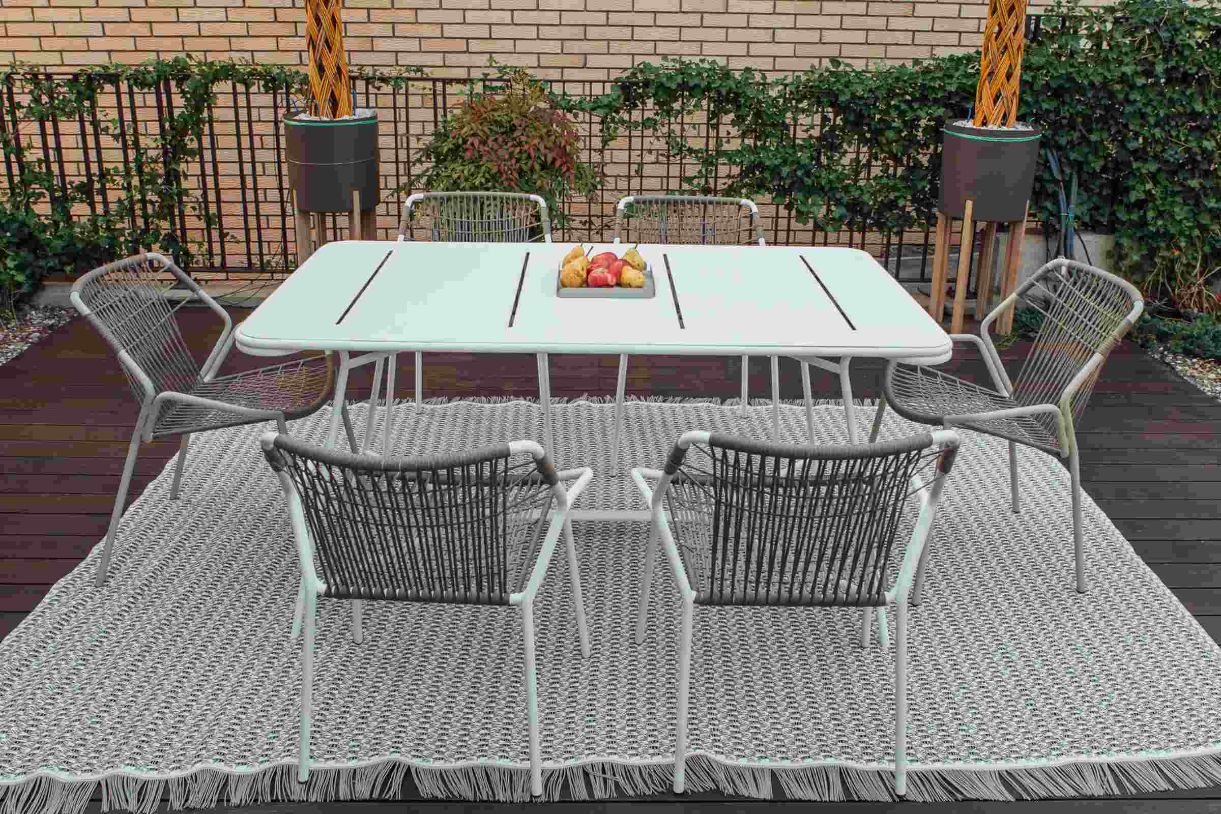 Outdoor-Gartentisch mit modernen Stühlen auf Holzterrasse