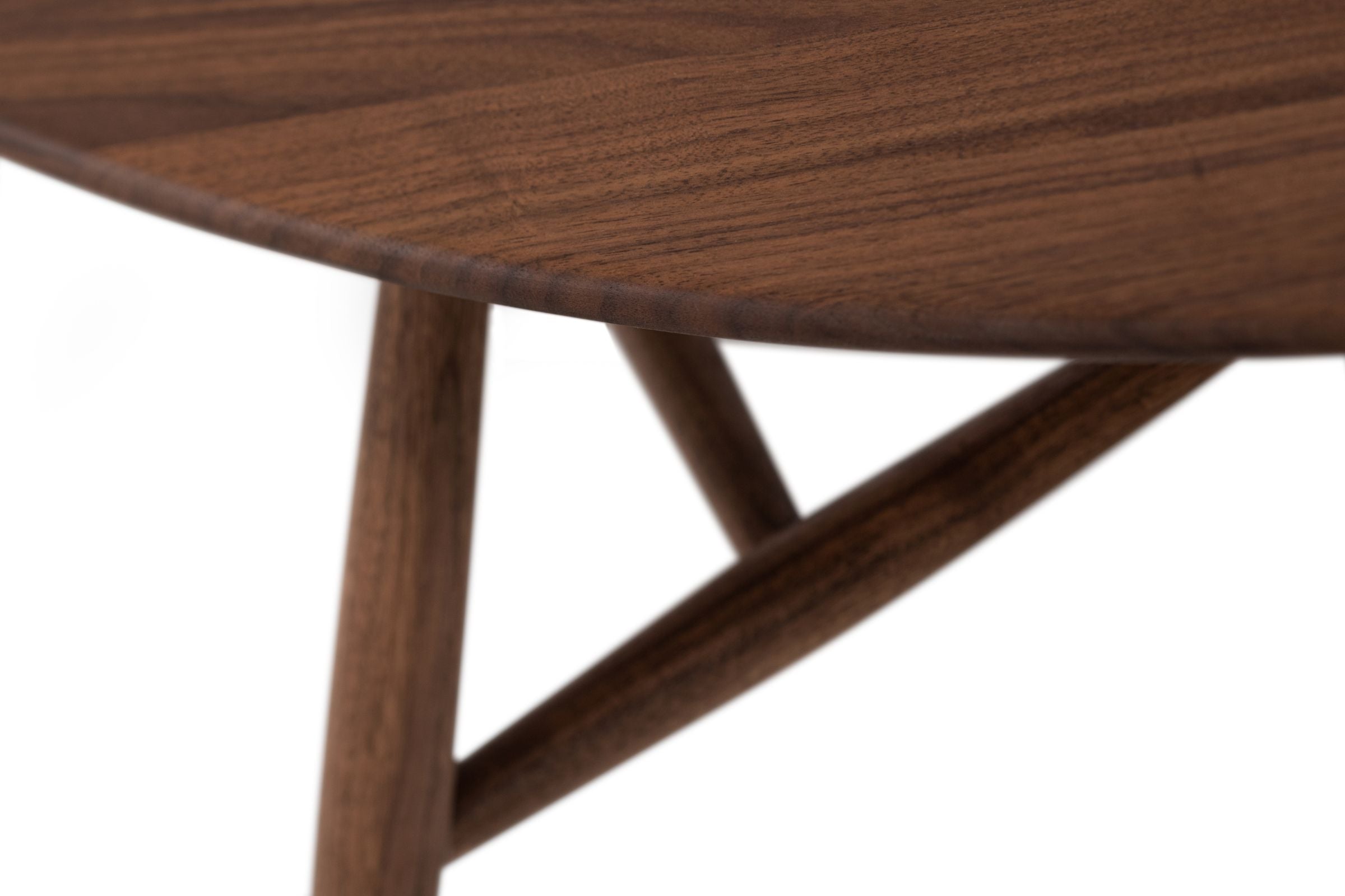 Nahaufnahme des TRIA Couchtisches von Woak, der eine detaillierte Ansicht der dunklen Holzmaserung und der glatten Kante der Tischplatte sowie der einzigartigen, gekreuzten Holzbeine zeigt