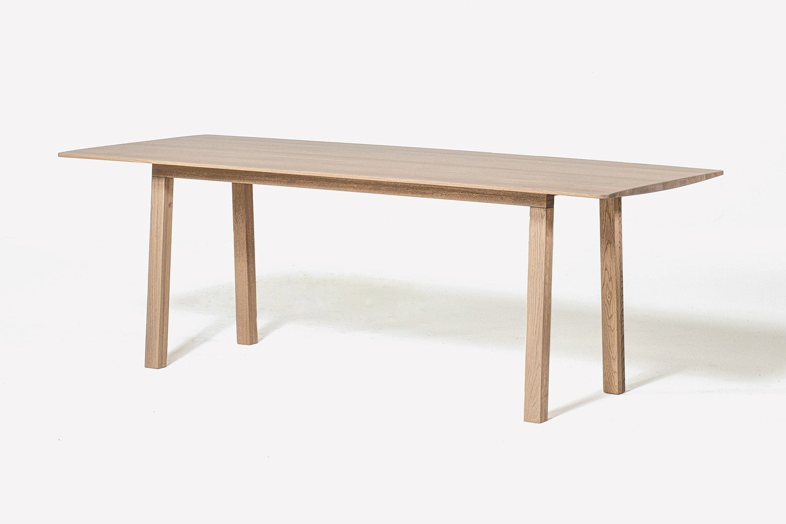 Ein hölzerner Esstisch mit einem rechteckigen Tischplatte und vier rechtwinkligen Beinen auf einem weißen Hintergrund.